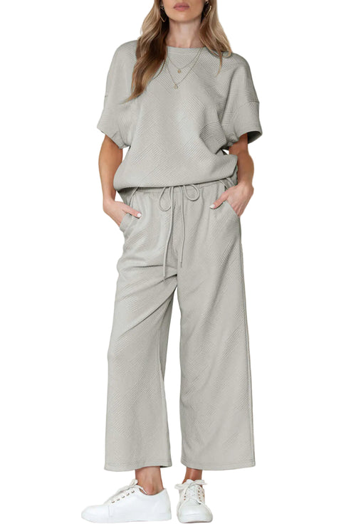 A woman wearing a green round-neck top and matching wide-leg pants with an elastic waistband, standing against a neutral background.