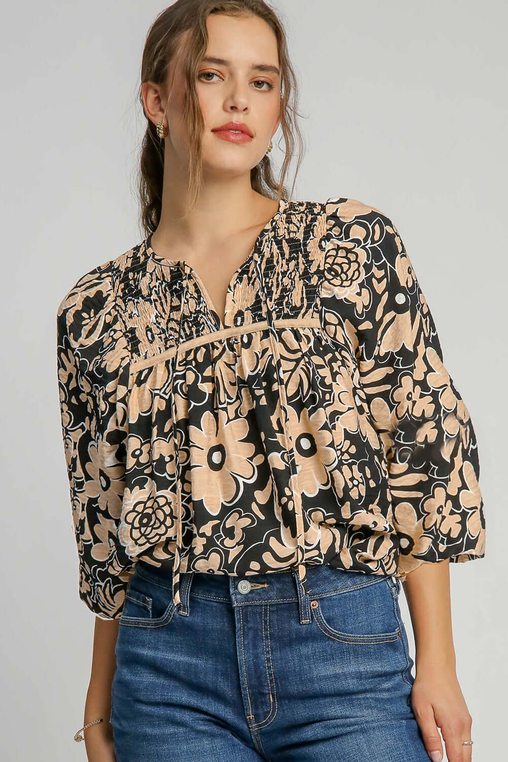Front view of a black floral boho blouse with half sleeves, styled on a standing model and paired with blue jeans for a casual chic look.
