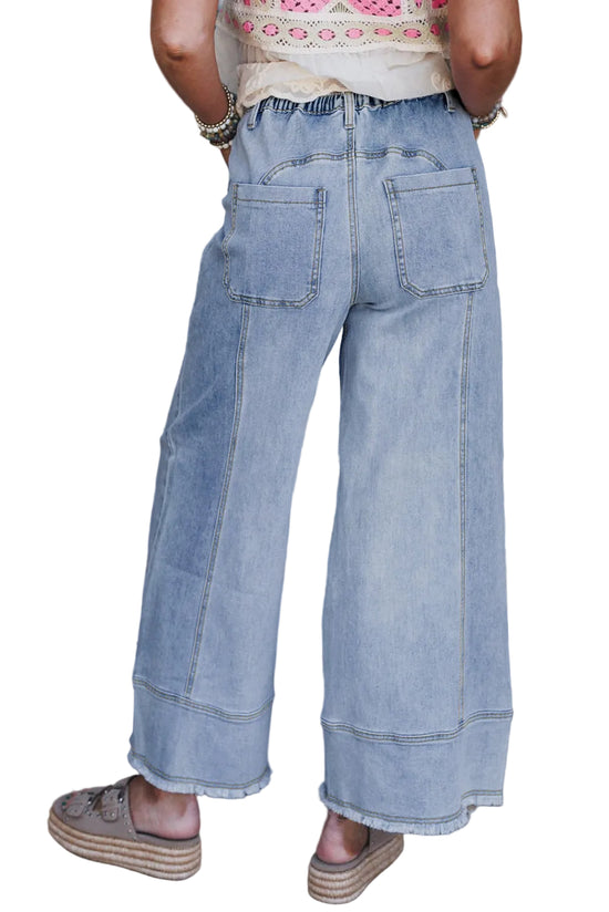 Person wearing light blue wide-leg jeans with a tie-dye pattern in the background