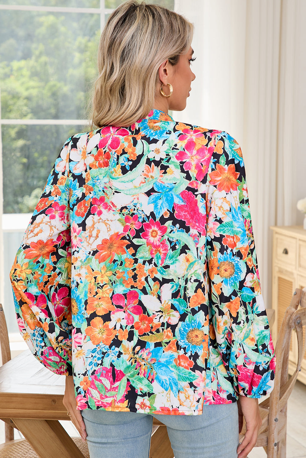 Back view of model wearing multicolour floral blouse with long lantern sleeves.