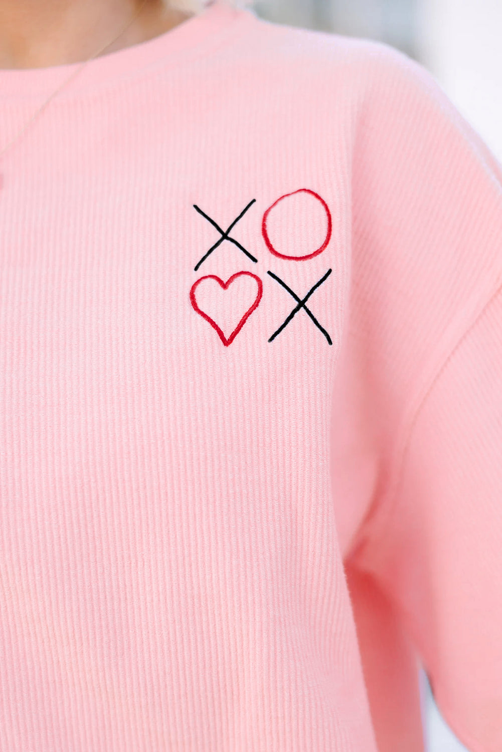 Pink shirt with 'XO' and heart design on a blurred background