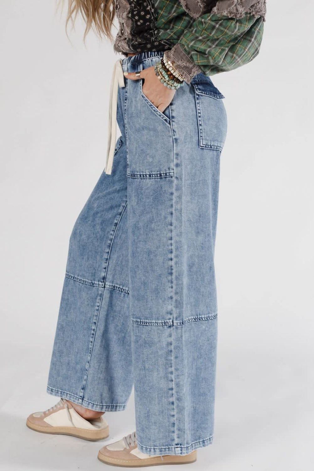 Person wearing wide-leg jeans and a plaid shirt on a plain background