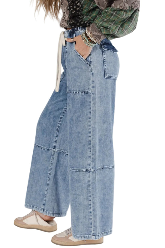 Person wearing wide-leg jeans and a plaid shirt on a plain background