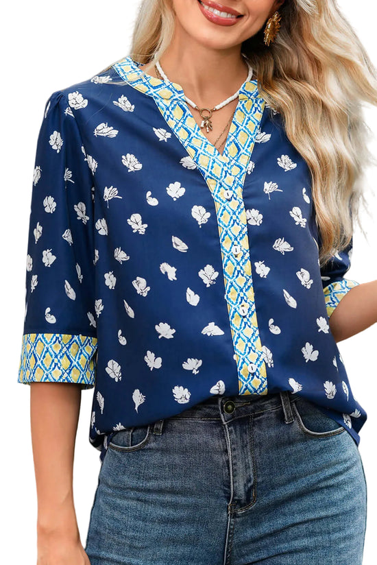 Woman wearing a blue floral blouse with a patterned collar and cuffs.