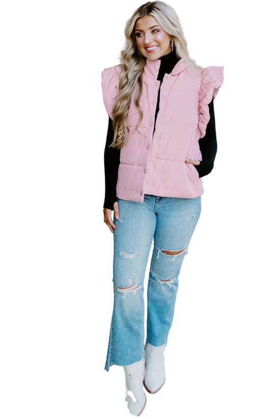 Woman wearing a pink vest, black turtleneck, and blue jeans on a patio.