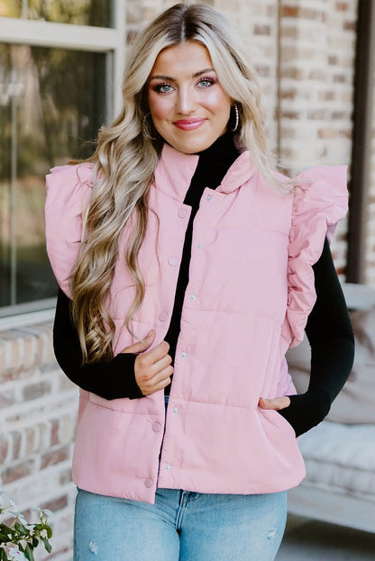 Woman wearing a pink puffer vest over a black top with a blurred background