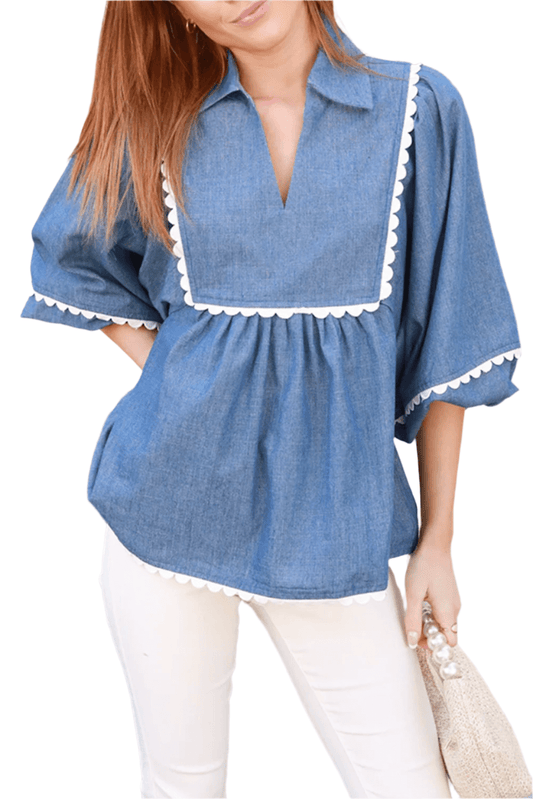 Woman wearing a blue denim blouse with white trim, standing outdoors.