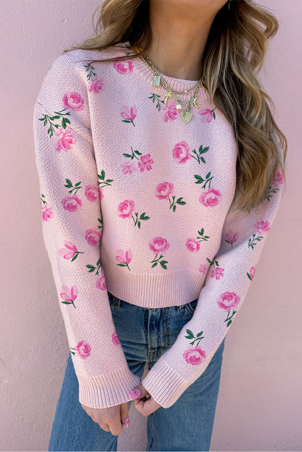 Pink floral sweater worn by a person against a pink background
