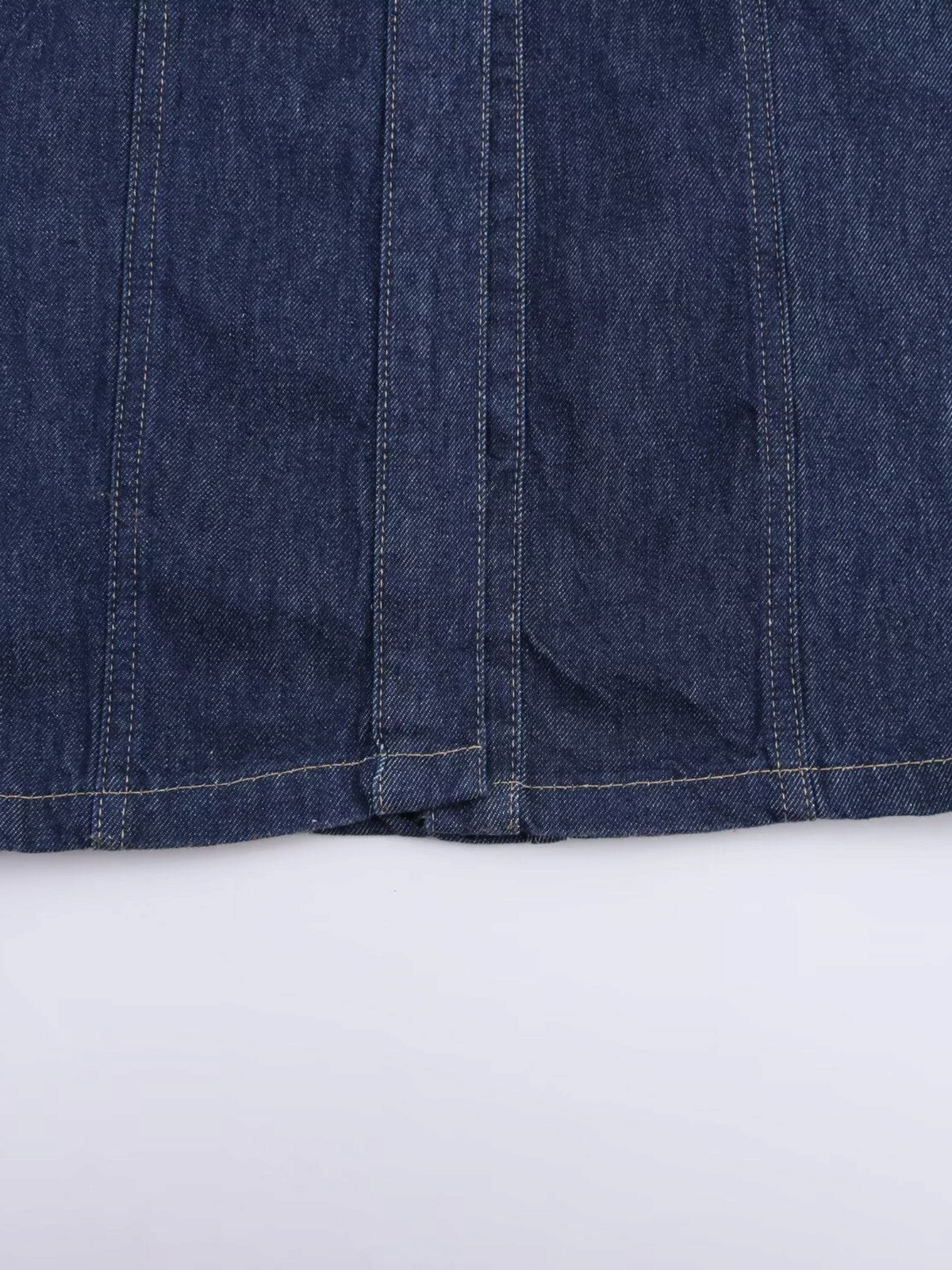 Close-up of the dark indigo denim fabric and vertical seam detailing on a Catherine Martin sleeveless maxi dress.