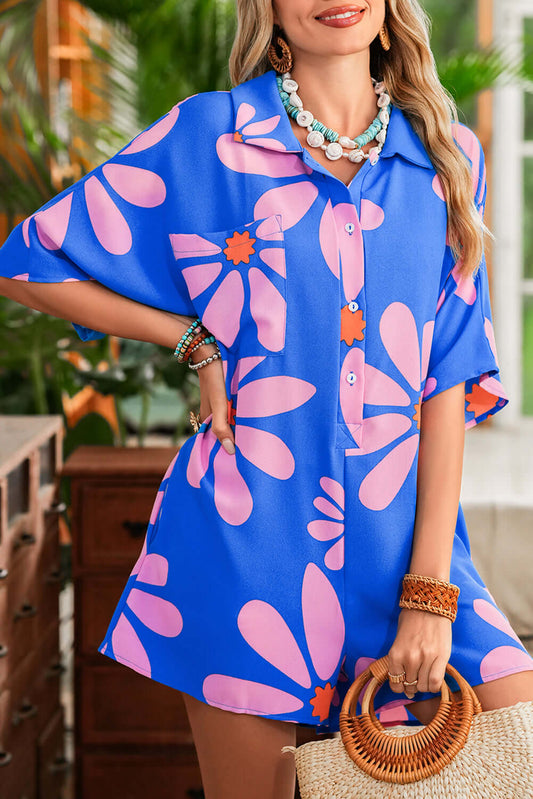 Woman wearing a blue dress with pink floral patterns, standing outdoors.