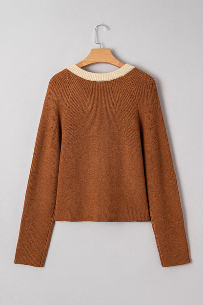 Brown sweater on a wooden hanger against a gray background