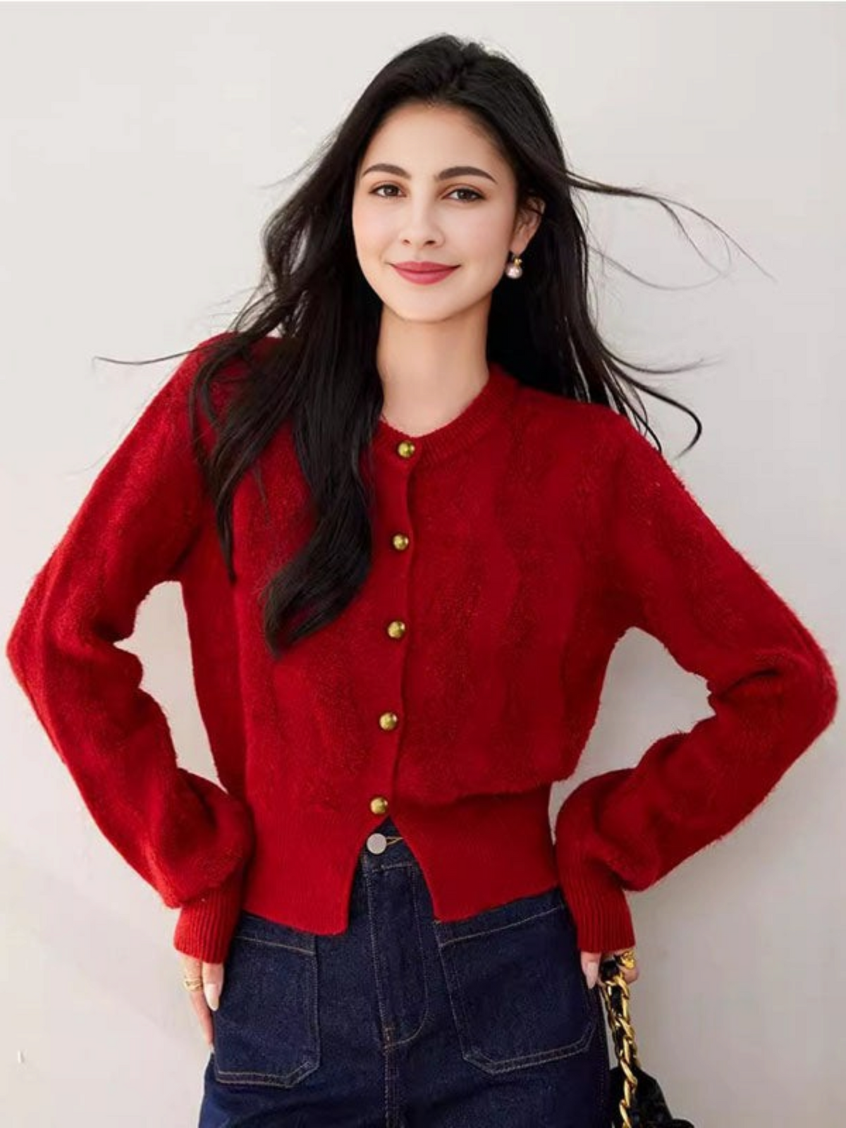 Catherine Martin red cropped knit cardigan with gold buttons, round neck, and long sleeves worn by a woman.