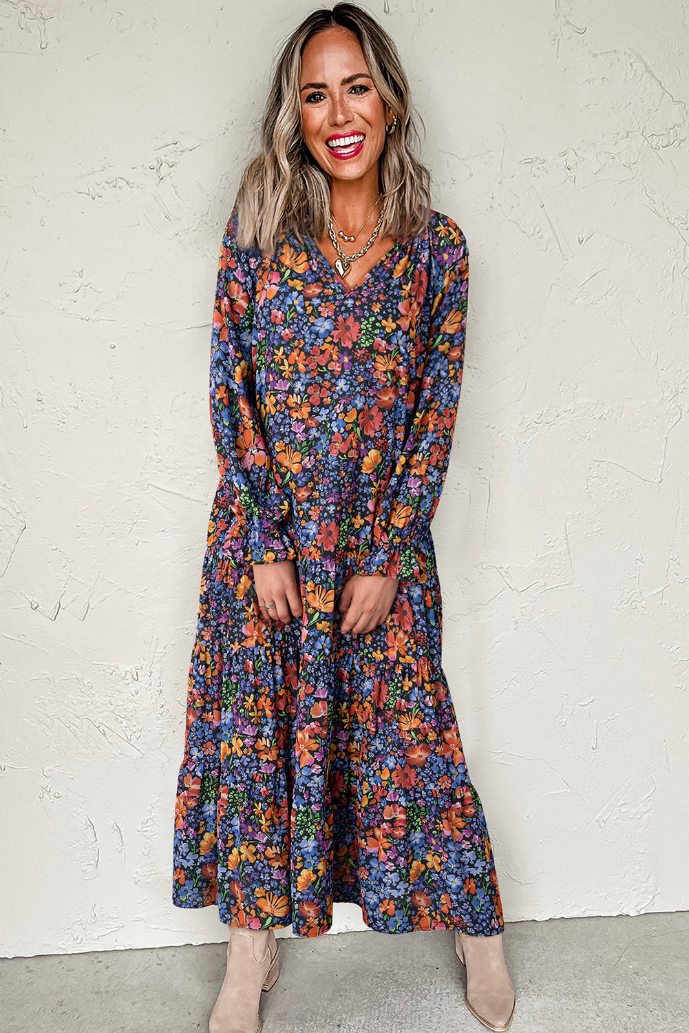 Woman wearing a long floral dress against a white wall