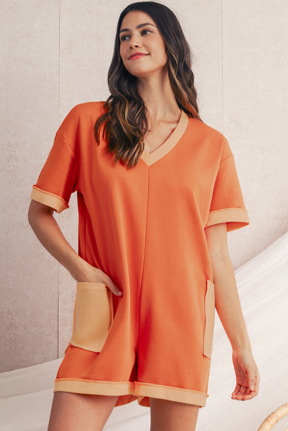 Woman wearing an orange dress with a neutral background
