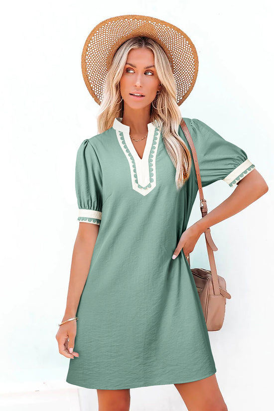 Woman wearing a green dress with white trim and a straw hat on a white background