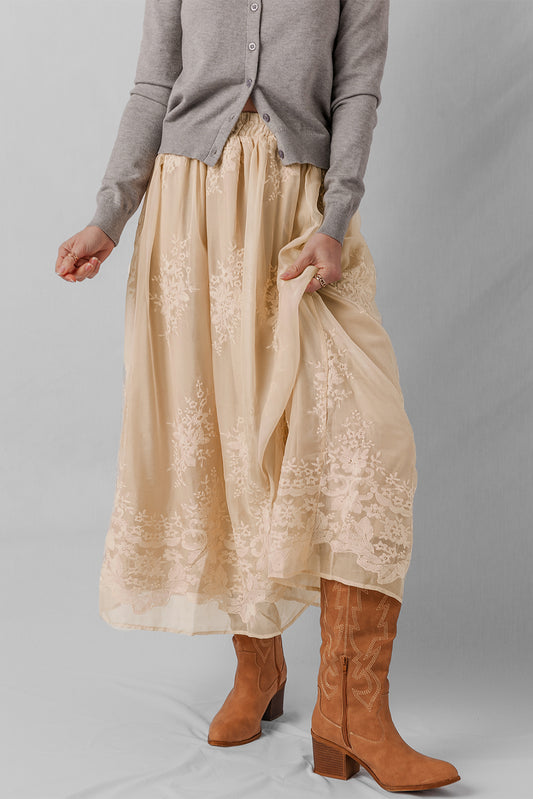 Person wearing a beige lace skirt with brown boots on a gray background