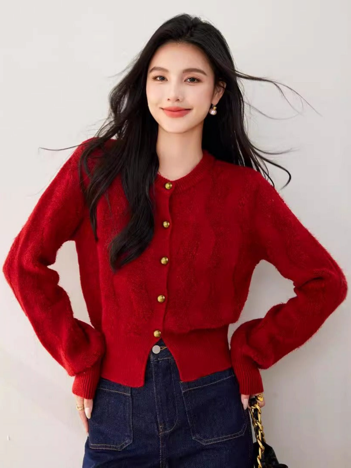 Catherine Martin red textured knit cardigan with gold buttons worn by a woman with dark hair and dark blue jeans