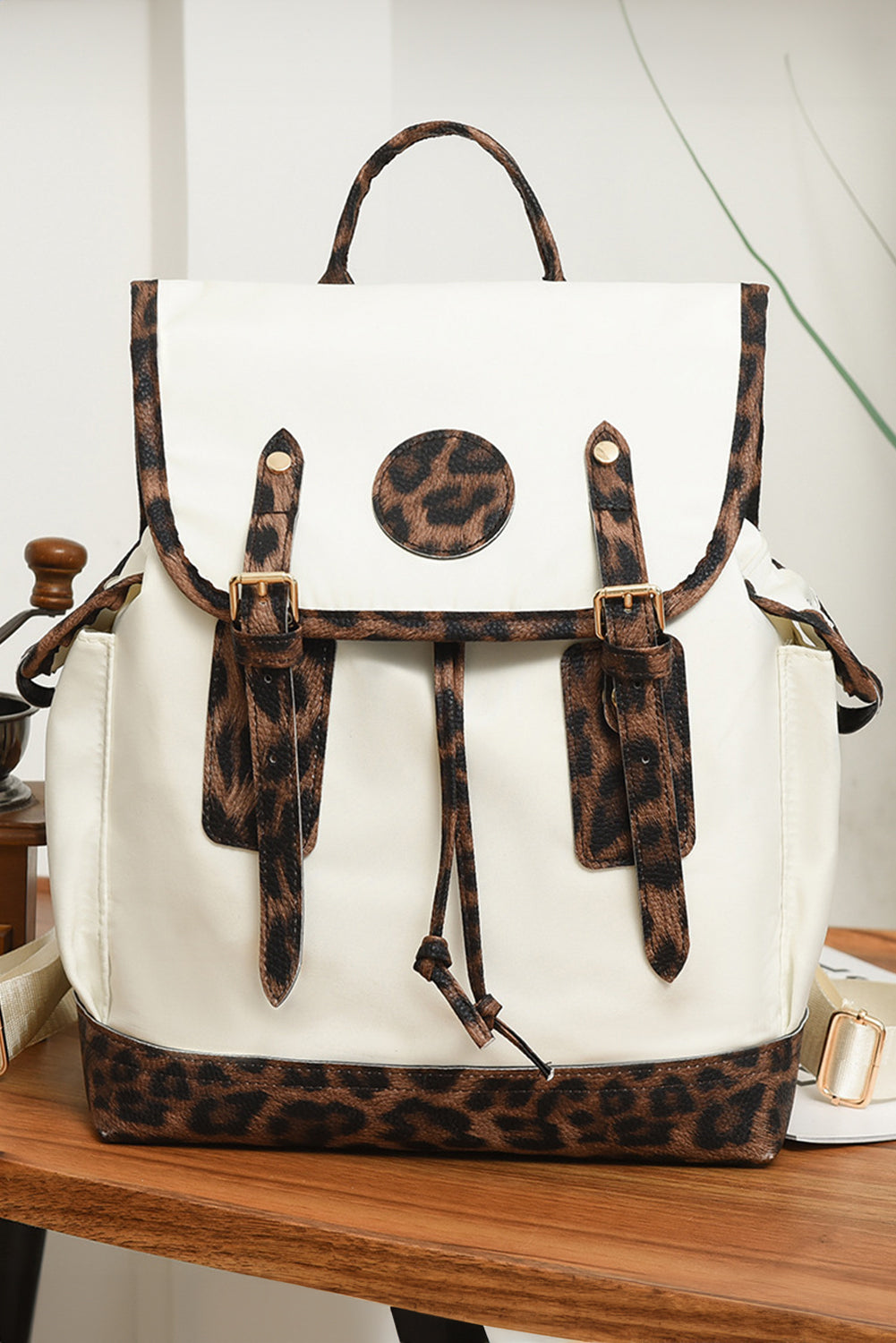White backpack with leopard print accents on a wooden surface