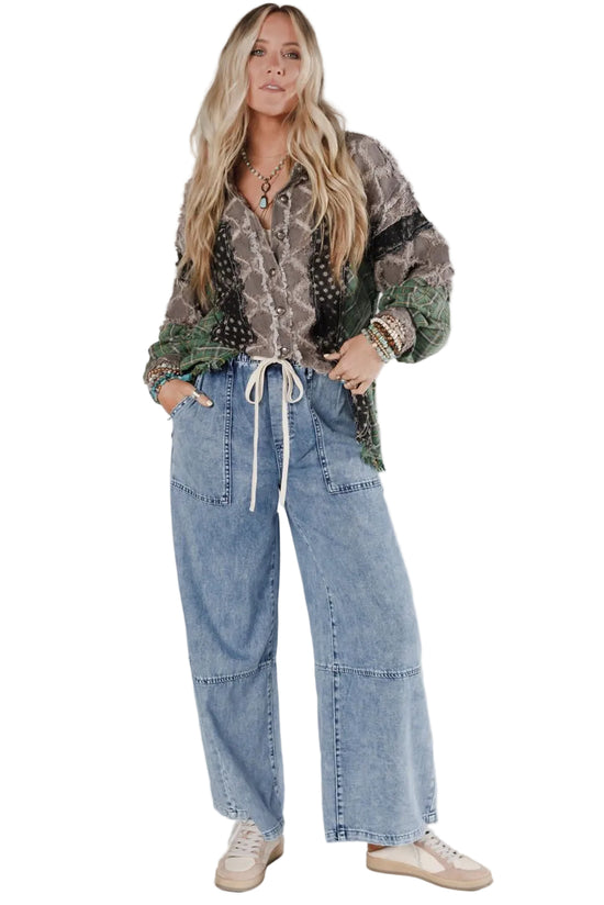 Woman wearing a patterned shirt and jeans on a white background