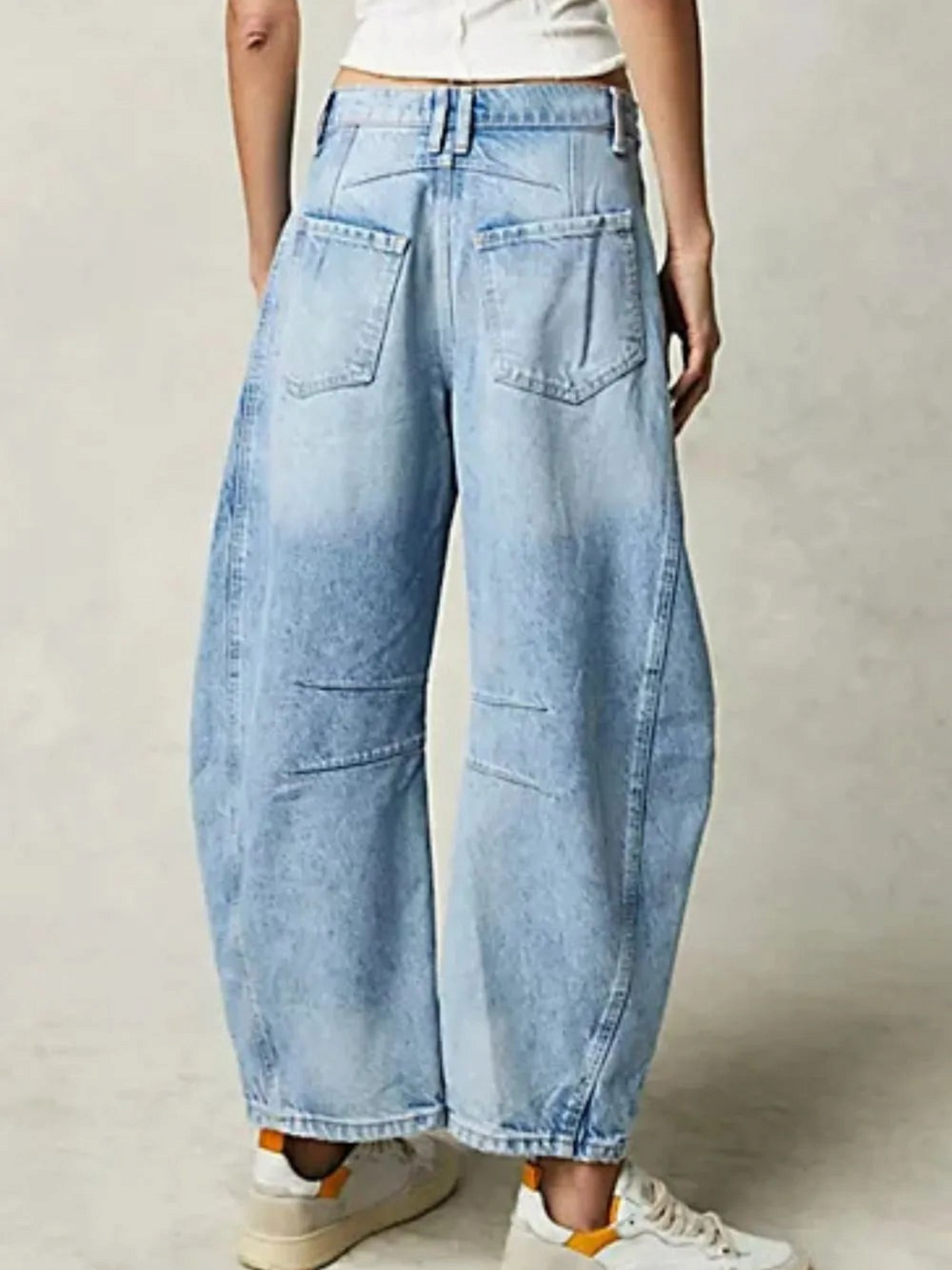 Catherine Martin light wash barrel leg jeans with a curved silhouette, back pockets, and knee seaming, rear view.