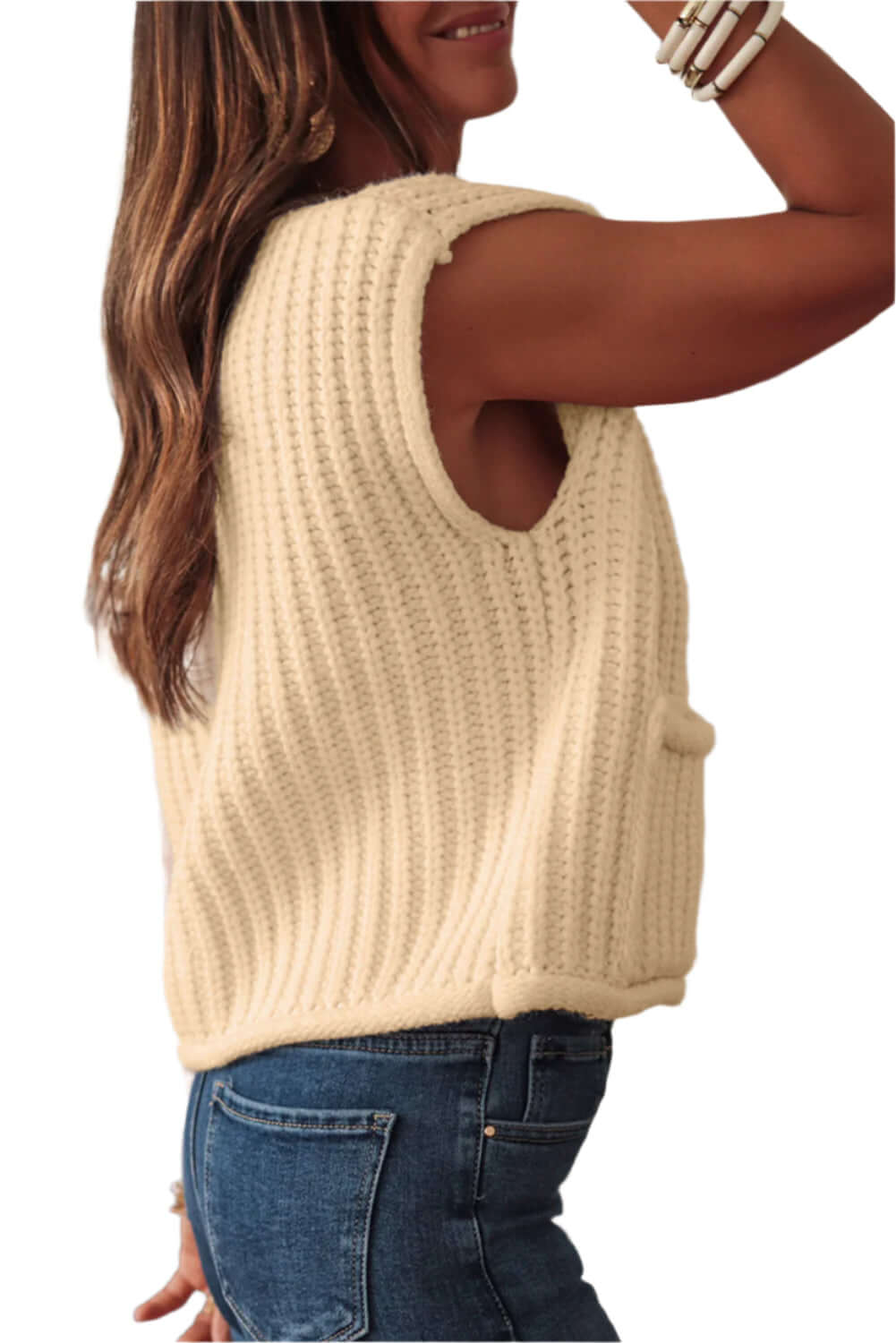 Trendy beige sleeveless cardigan layered over a fitted top for a chic look.
