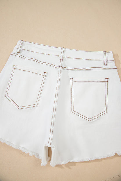 White denim shorts with frayed hem on a beige background
