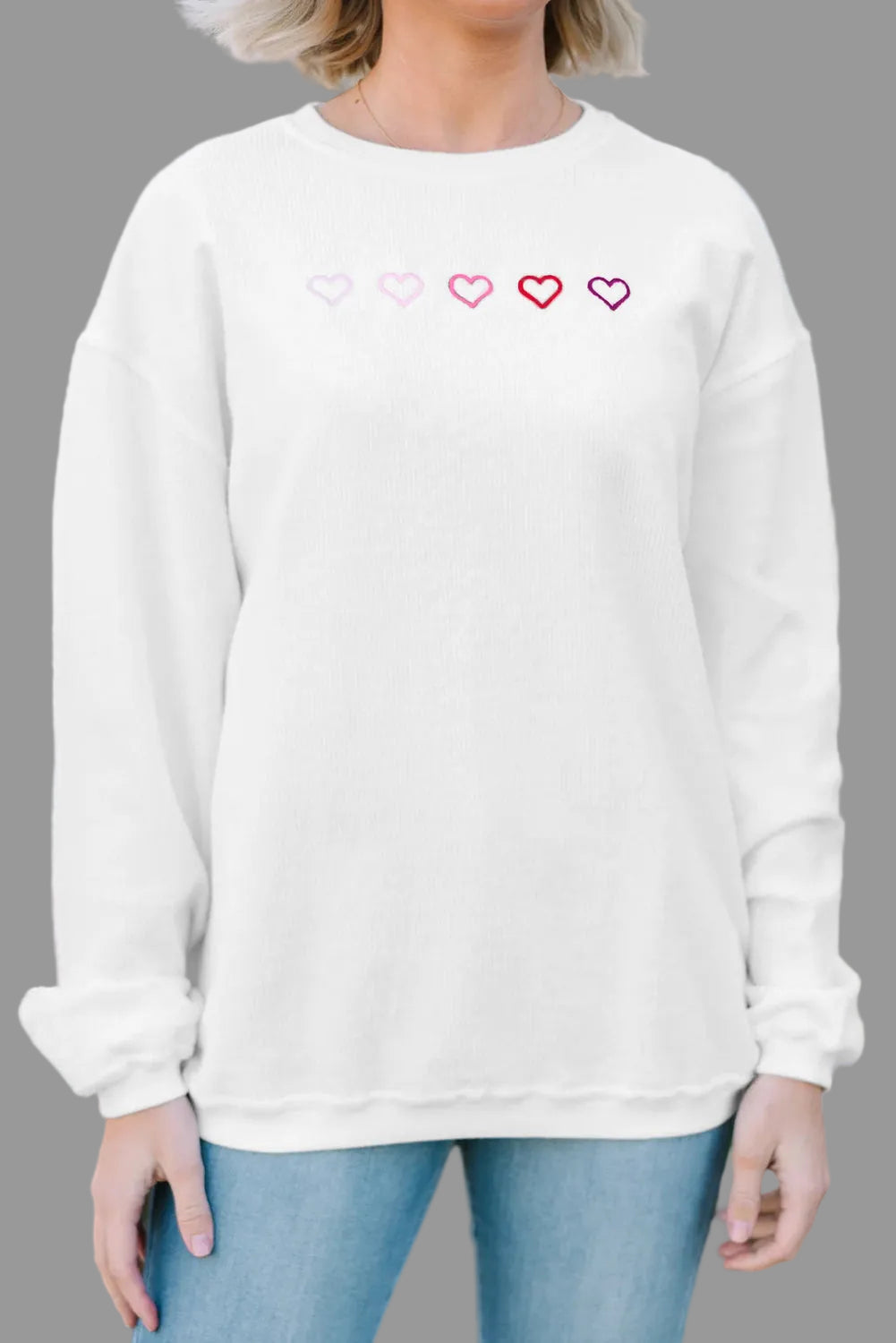 White sweatshirt with heart designs worn by a person outdoors