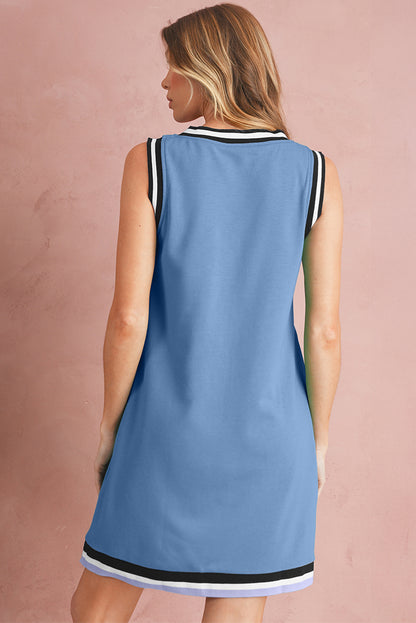 Woman wearing a blue sleeveless dress with black trim against a pink background