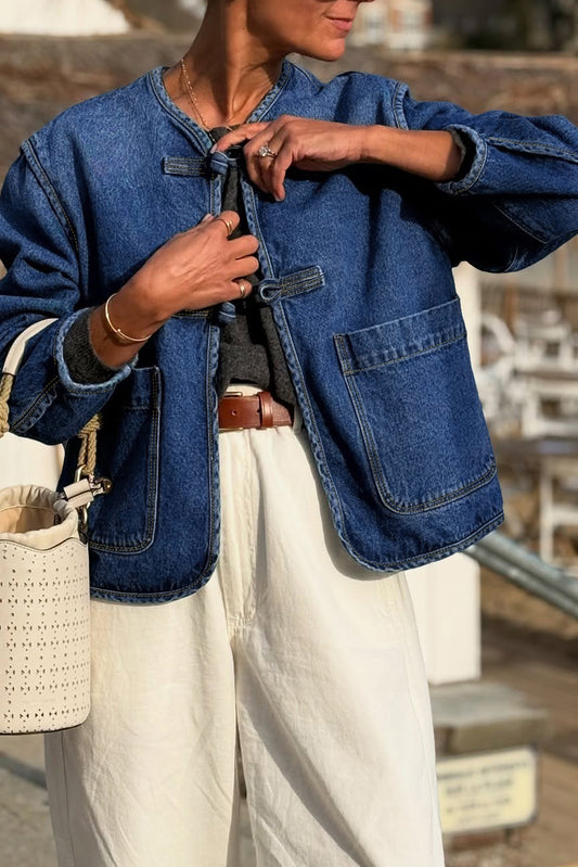 Person wearing a blue denim jacket and white pants outdoors.