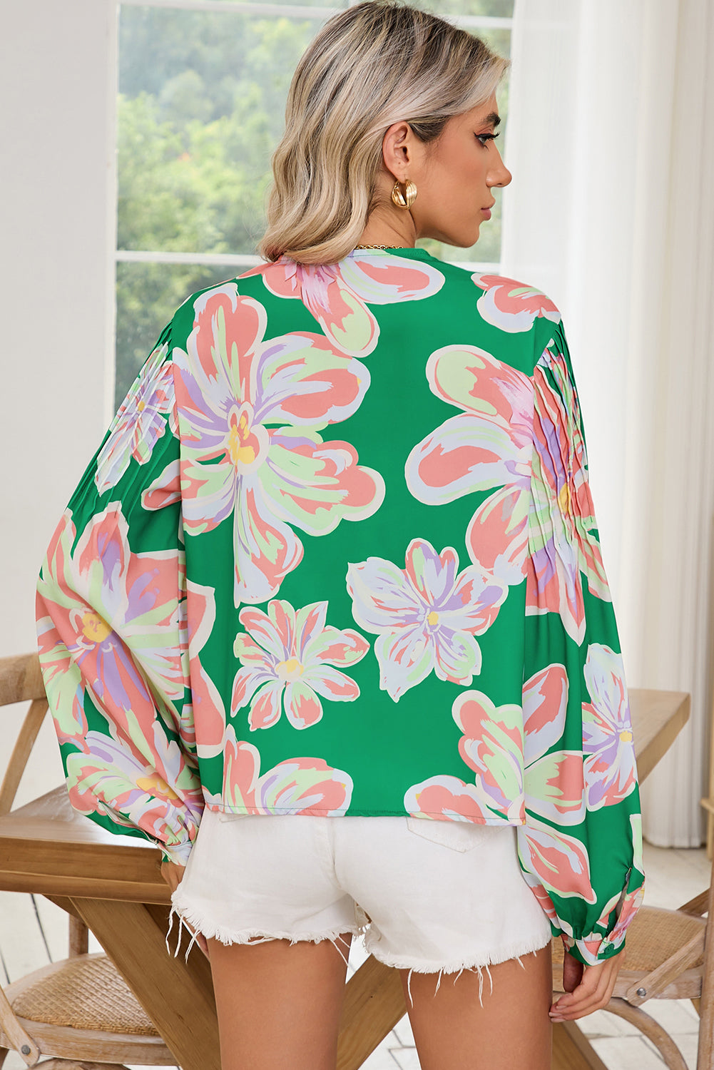 The back view of green floral blouse, featuring pleated long sleeves.