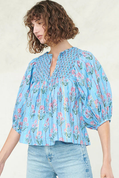 Model standing in a light blue striped floral blouse with half sleeves.