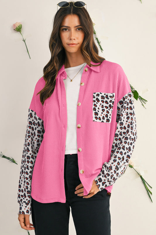 Woman wearing a pink shirt with leopard print sleeves and pocket on a light background