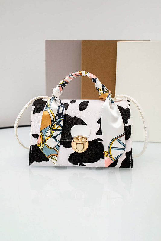 Handbag with cow print and colorful handle on a white surface