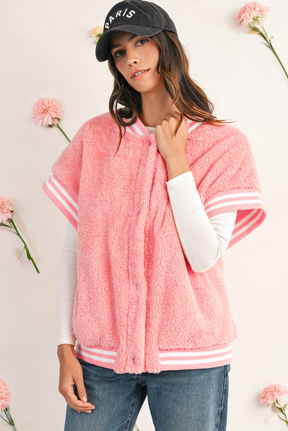Woman wearing a pink fleece jacket with white trim, standing against a light background with flowers.