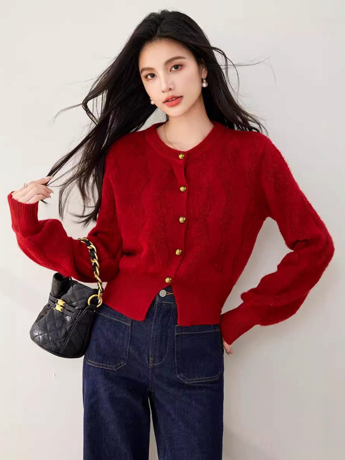 Catherine Martin red cropped knit cardigan with gold buttons worn by a model with dark hair and a black handbag