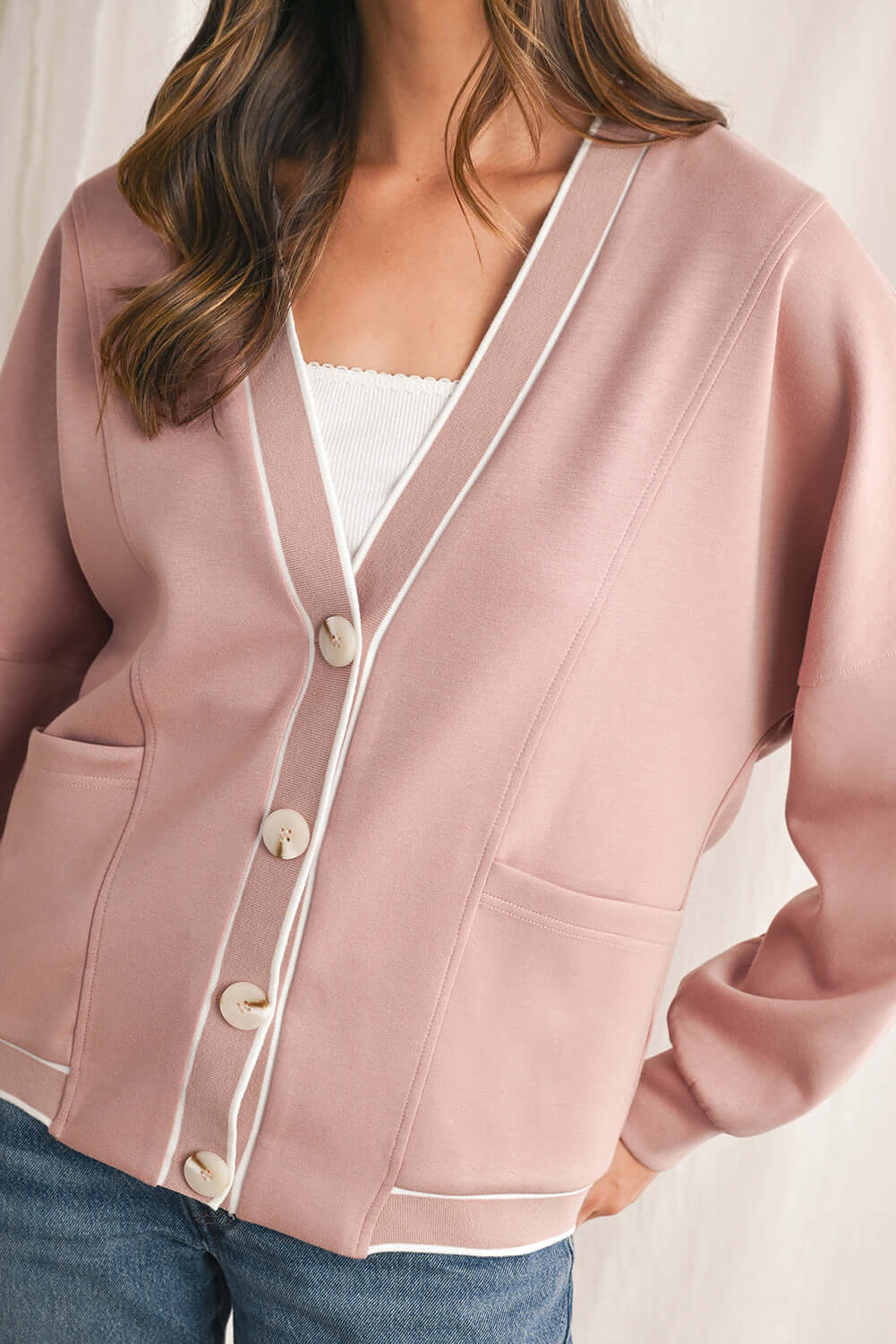 Close-up of the texture of a pink striped cardigan with long sleeves.