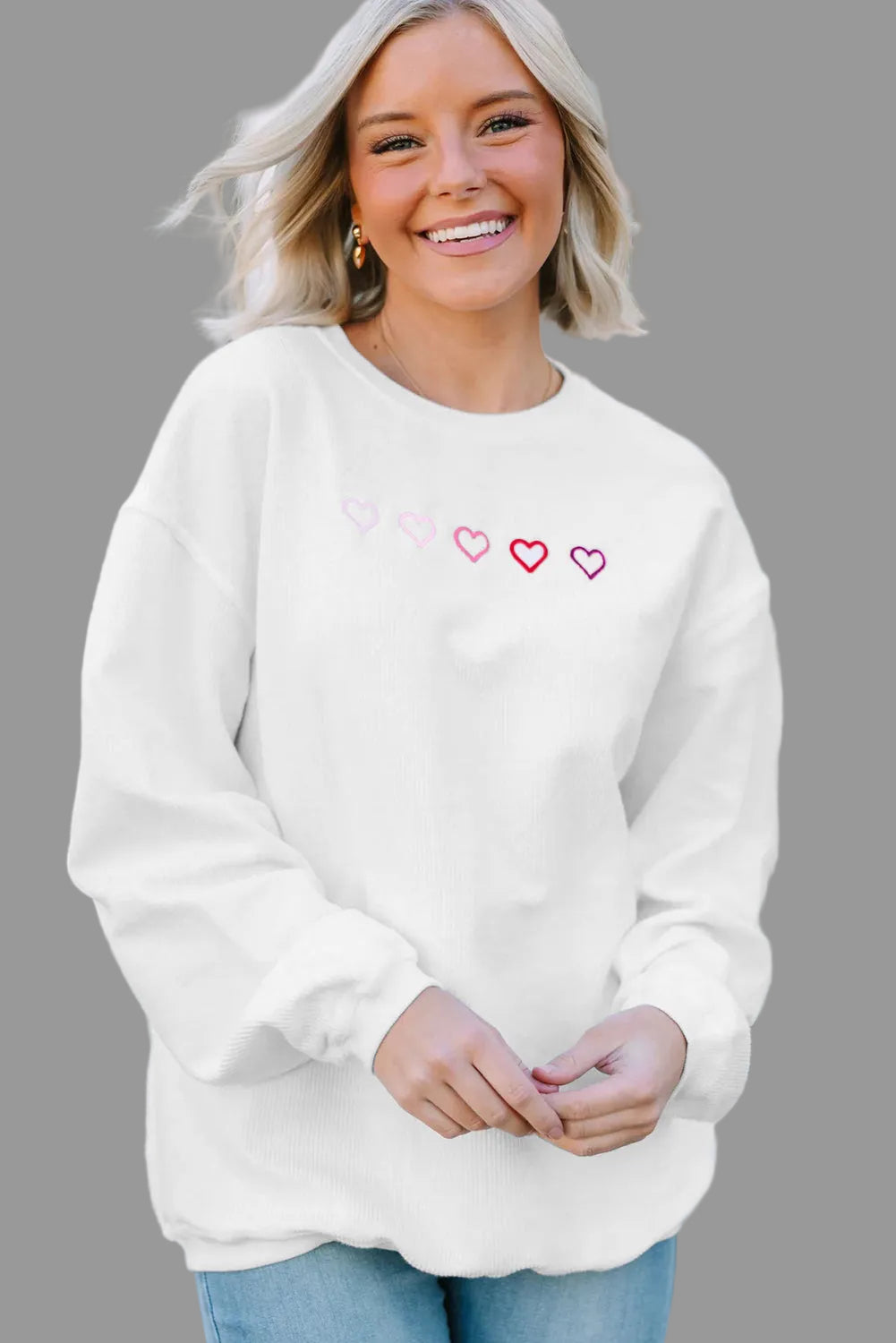 Woman wearing a white sweatshirt with heart designs outdoors