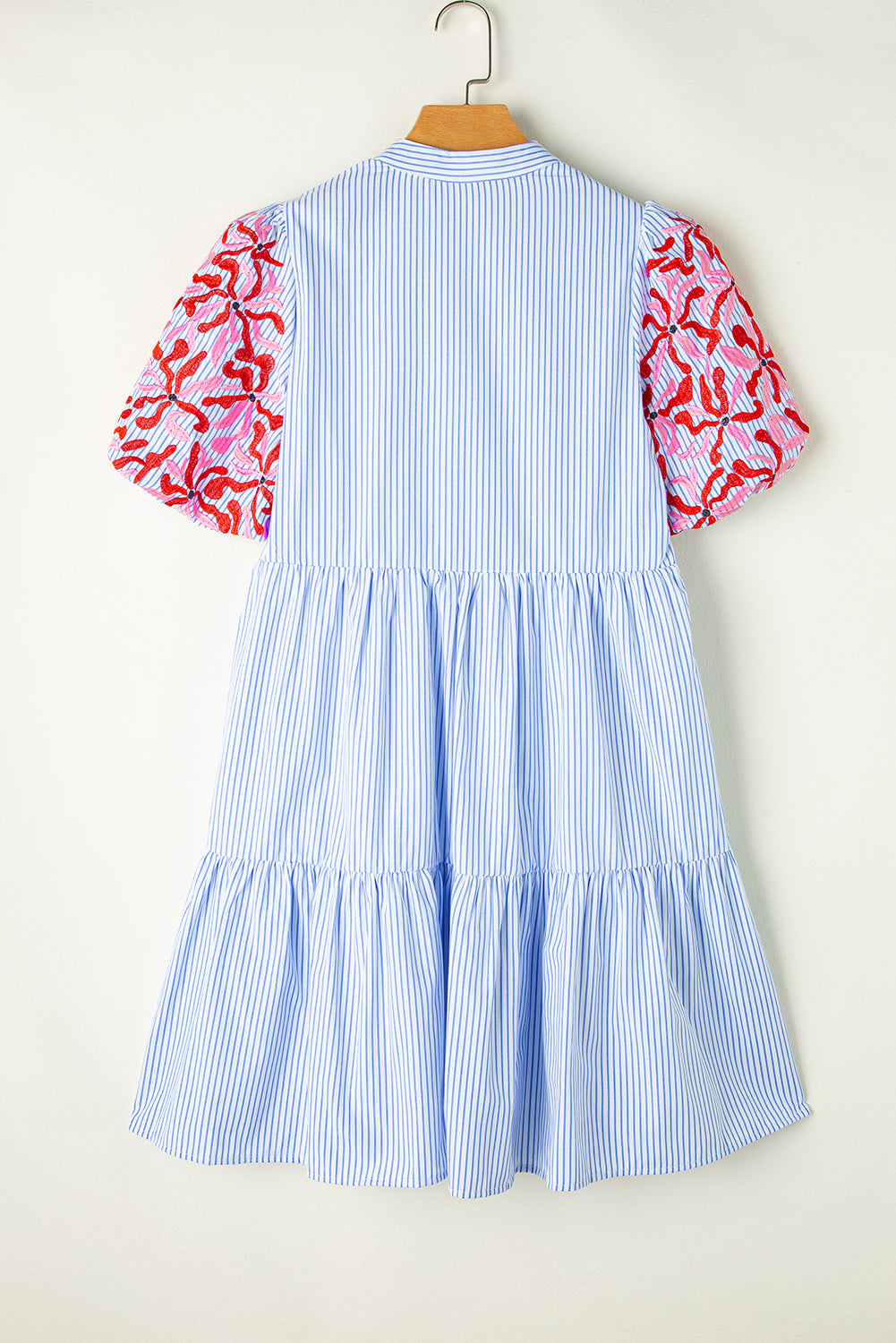 Back view of blue striped tiered mini dress with floral red and pink puff sleeves.