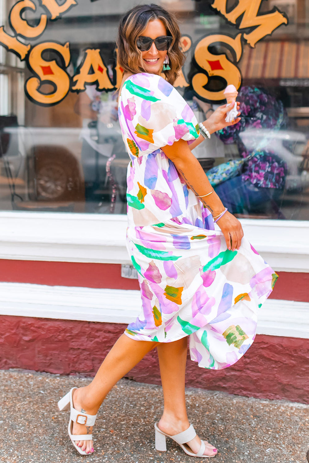 Side view of purple abstract print dress with short bubble sleeves on a model.