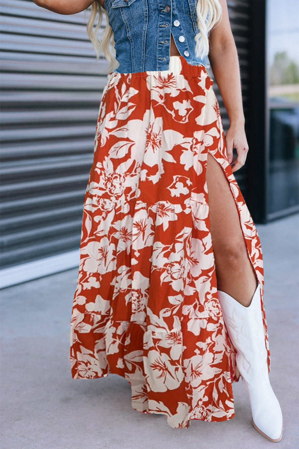 Person wearing a red floral skirt with a slit, denim jacket, and white boots.