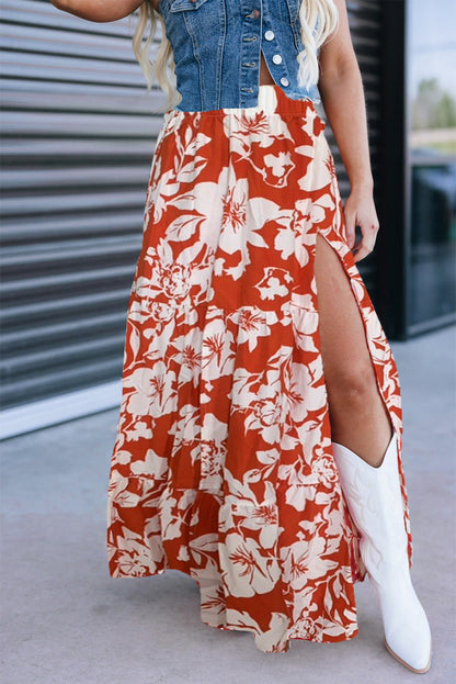 Person wearing a red floral skirt with a slit, denim jacket, and white boots.