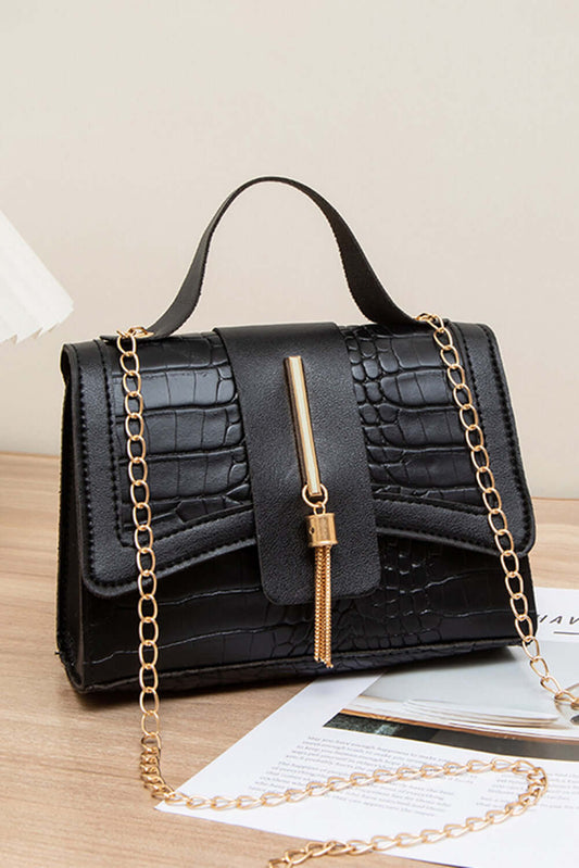 Black handbag with gold chain strap on a wooden surface