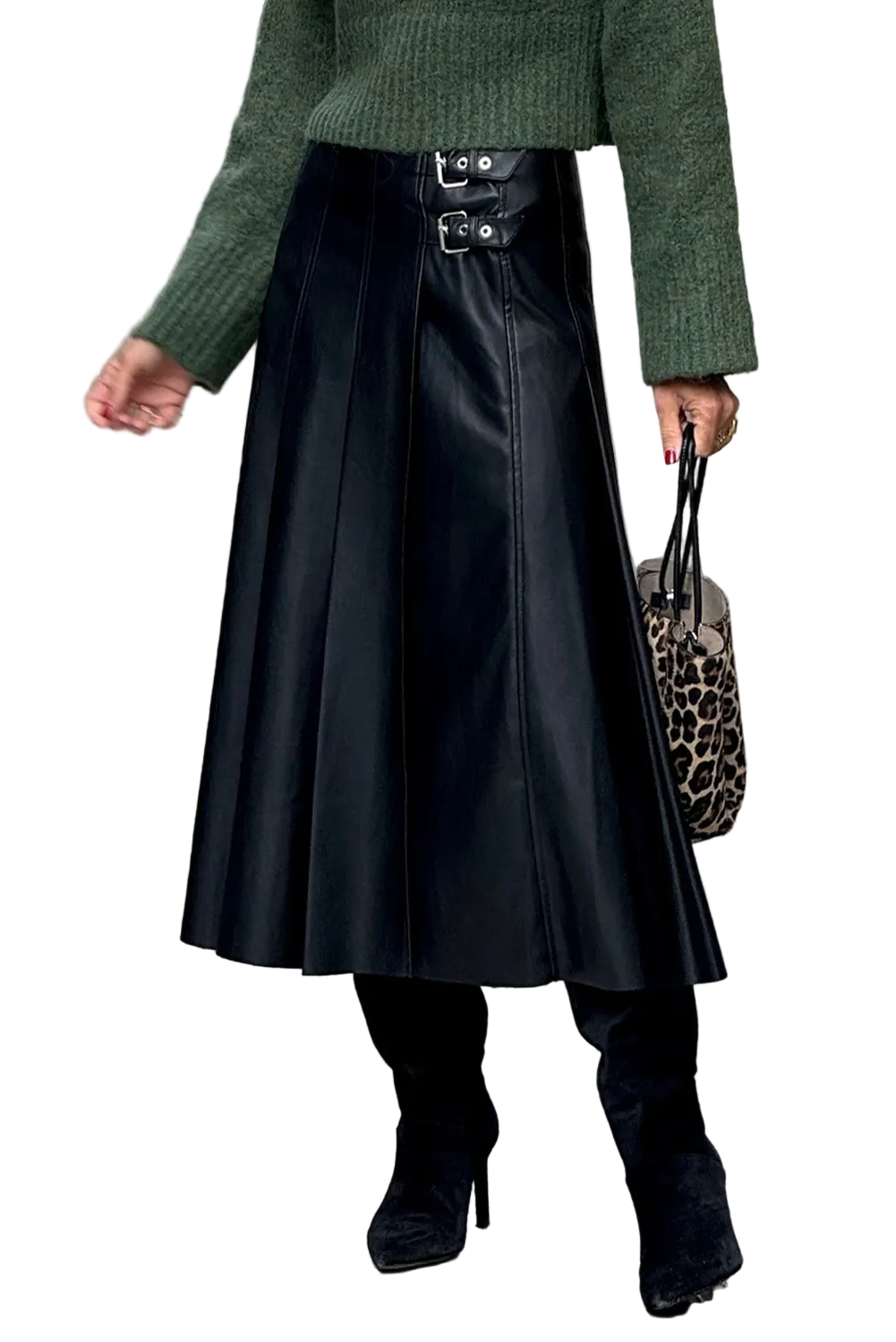 Person wearing a green sweater, black leather skirt, and black shoes on a city street.