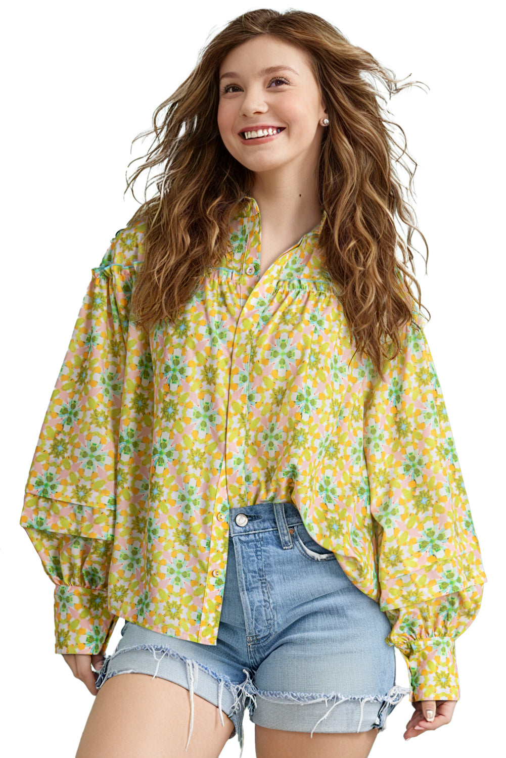 Model wearing a green and yellow floral blouse with denim shorts against a white background.