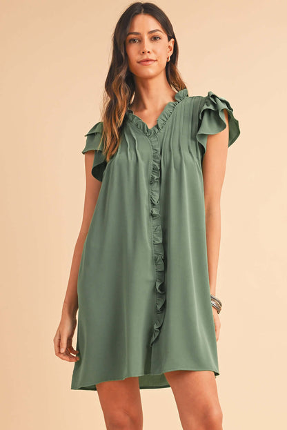Woman wearing a short ruffle front dress with flutter sleeves and V-neckline.