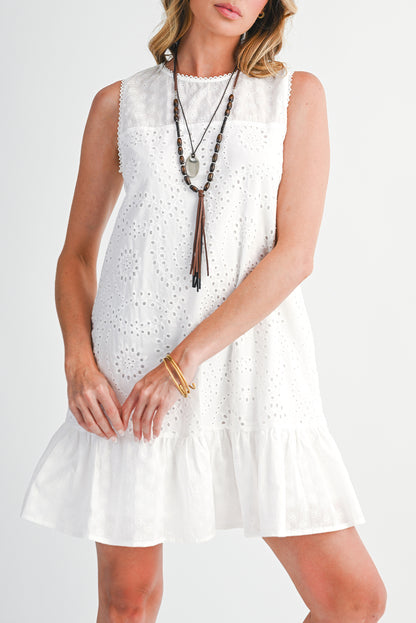Woman wearing a white sleeveless dress with a necklace on a plain background