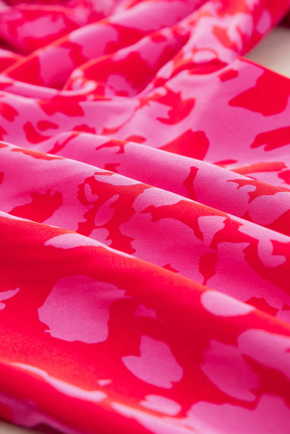 Vibrant pink satin jumpsuit with statement sleeves and belted waist. Fabric view.
