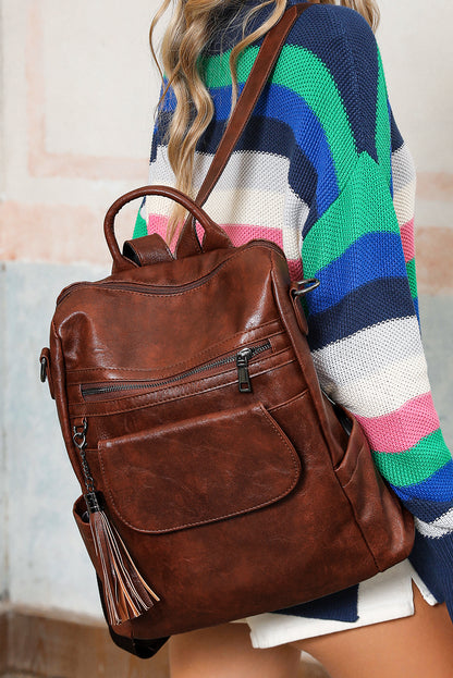 Brown leather backpack worn by a person with a colorful striped sweater.
