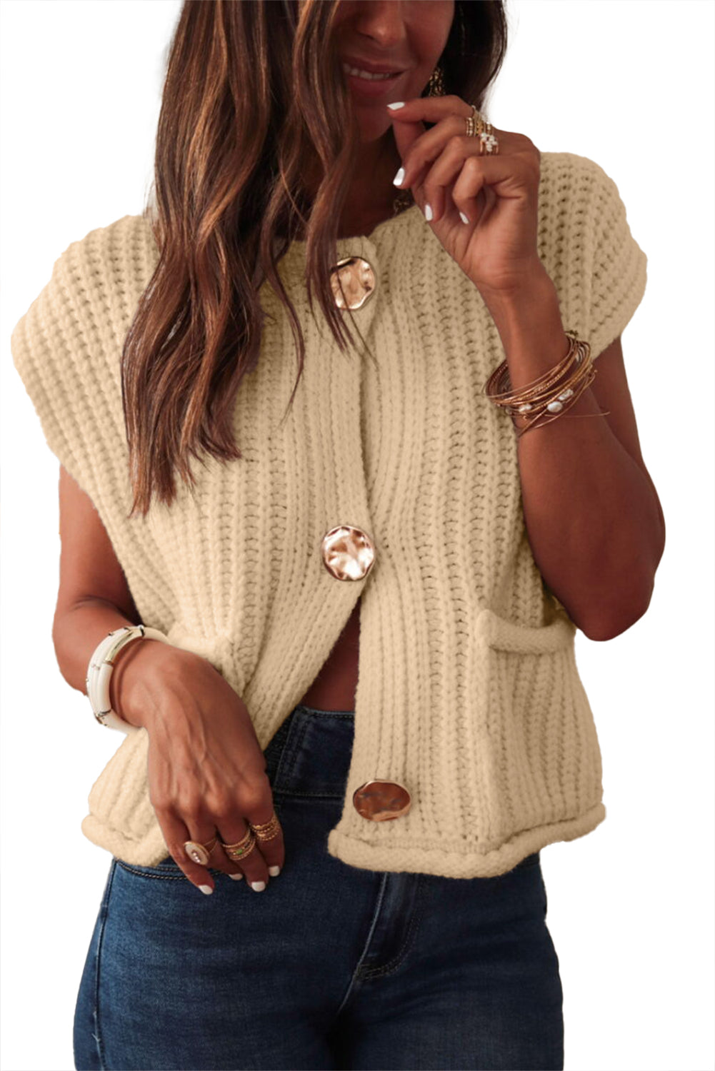 Trendy beige sleeveless cardigan layered over a fitted top for a chic look.
