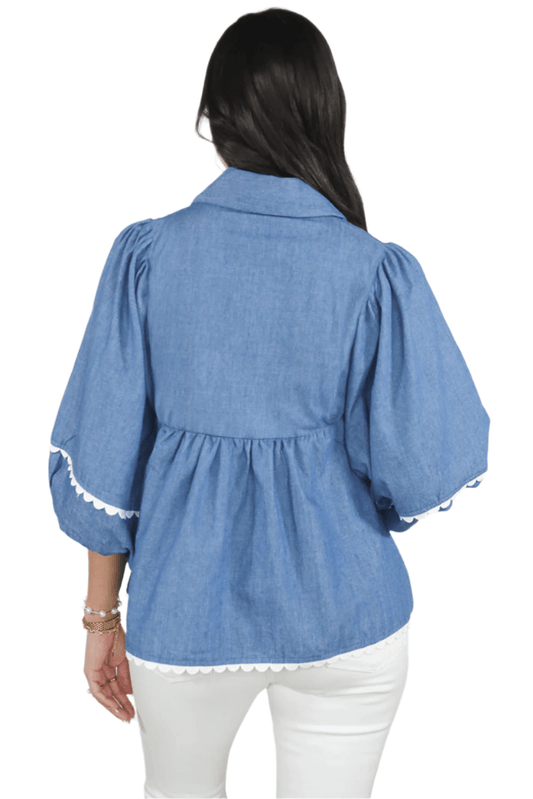Woman wearing a blue denim shirt with lace trim on a white background